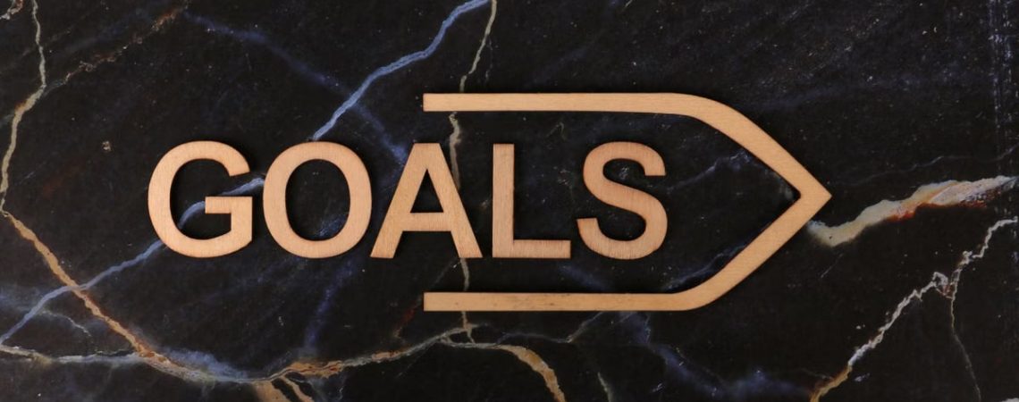 Inspiring image of a wooden 'GOALS' sign on a dark marble surface, symbolizing ambition.